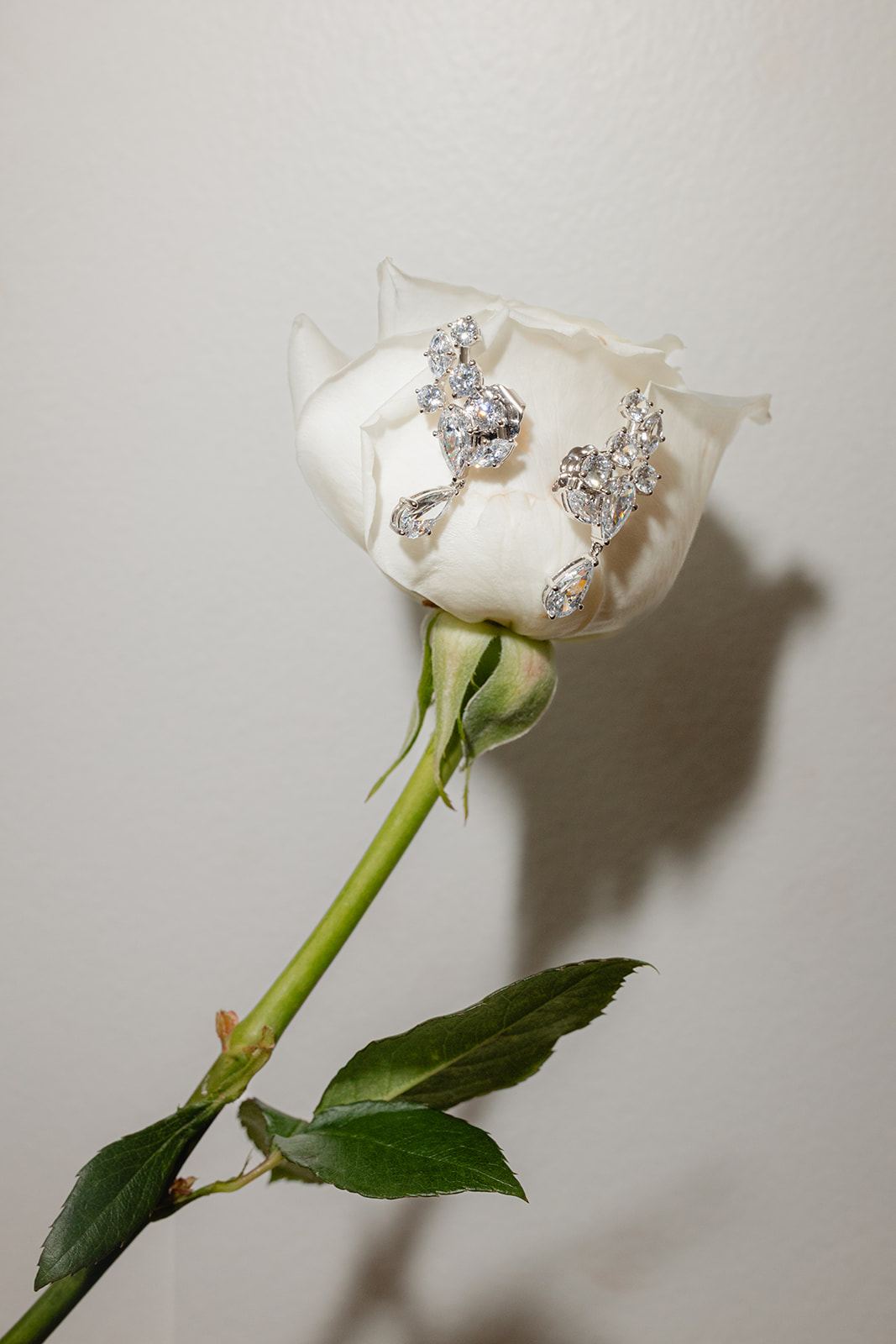 Diamond earrings pinned to a single white rose