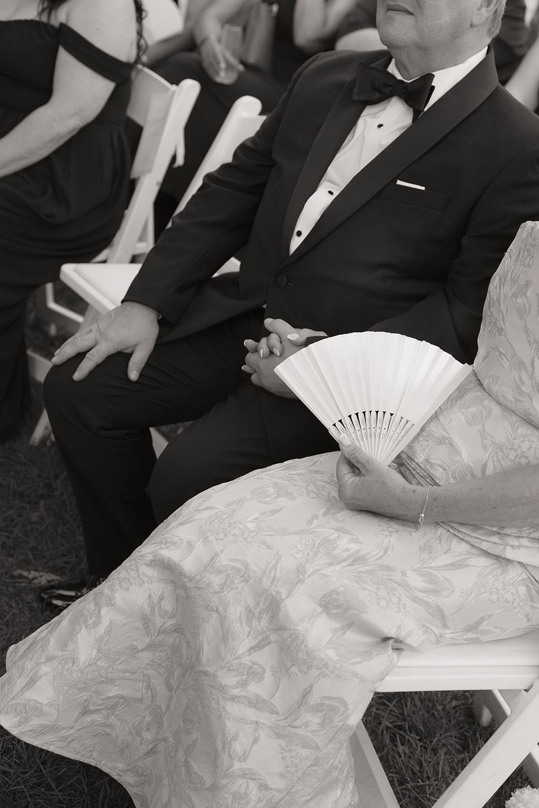 Guest holding a white fan at the ceremony, black and white