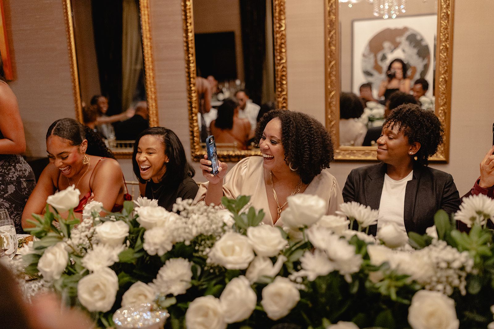 Guests laughing at a reception table filled with white roses