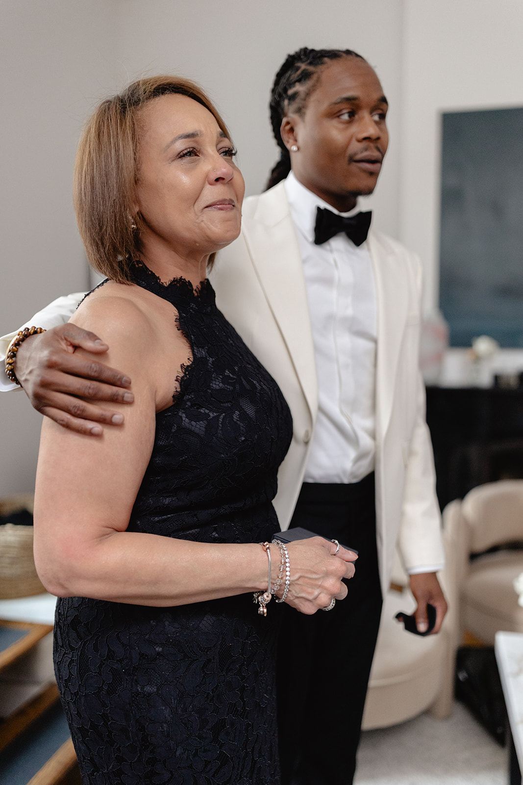 Groom in a white tuxedo jacket hugging a woman in navy lace