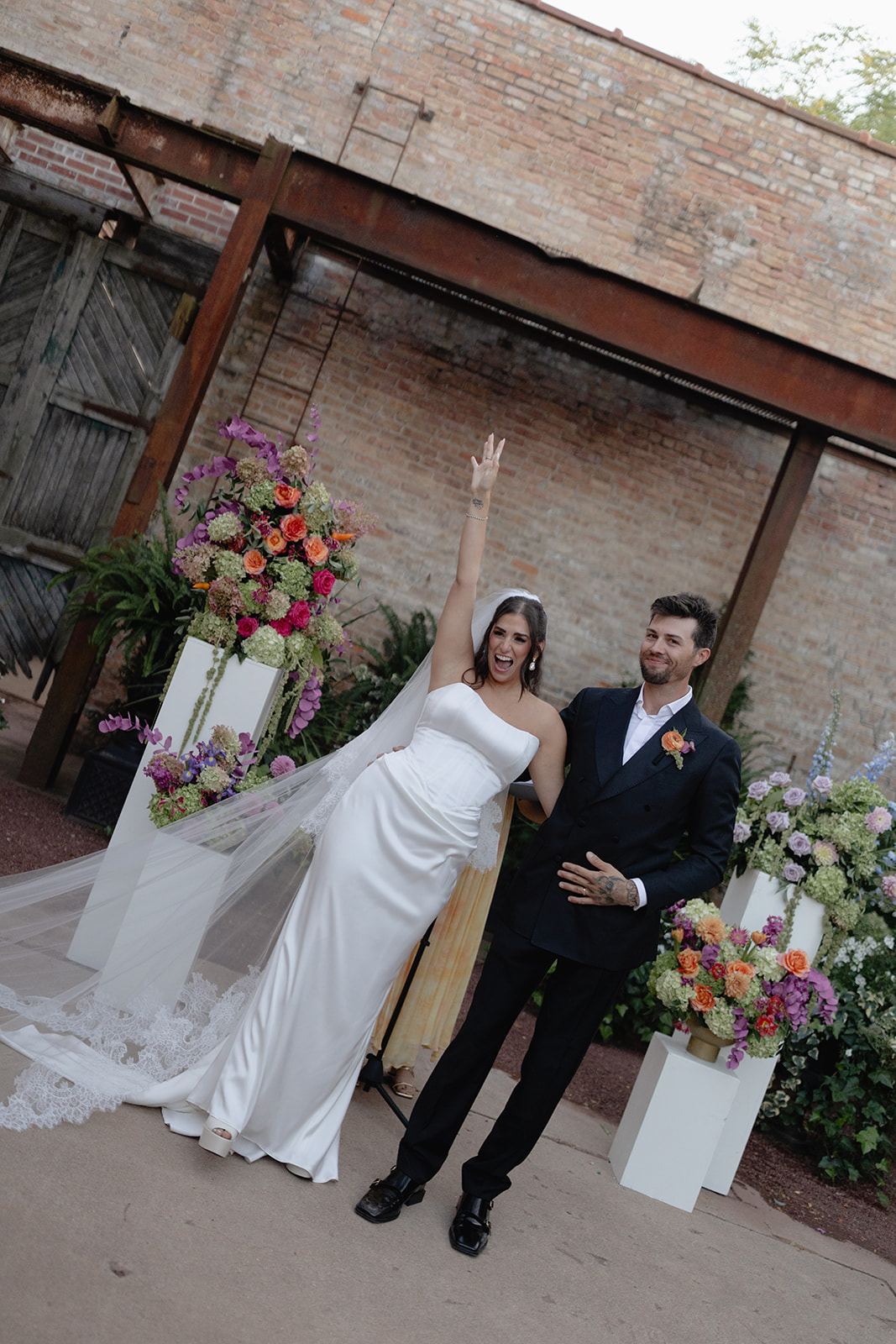 Bride raising her arm in celebration beside the groom at the altar